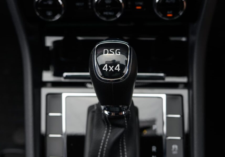 Pomello in pelle del cambio automatico DSG 4x4 (Direct-Shift Gearbox) di un'automobile del Gruppo Volkswagen, con cuciture bianche e console centrale scura sullo sfondo.